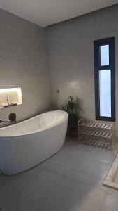 a large white bath tub in a bathroom with a window at Royal chalet in Al Qurayyat