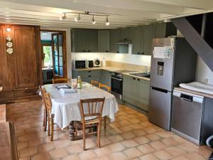 una cucina con tavolo con sedie e frigorifero di Maison indépendante avec grand jardin, terrasse, plan d'eau sécurisé et salle de jeux près du lac d'Éguzon - FR-1-591-216 a Bazaiges