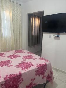 a bedroom with a bed and a flat screen tv at Kitnet Luar in São Thomé das Letras