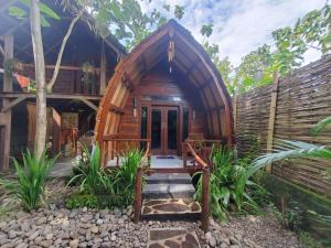 a cabin with a wooden door in a forest at Pondok Kebun Jati in Pawenang
