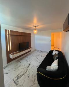 a living room with a black couch and a flat screen tv at 1912 Boutique Hotel in Cayey