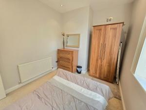 a bedroom with a bed and a wooden cabinet at Exquisite 2 Bedroom Apartment in Sheffield