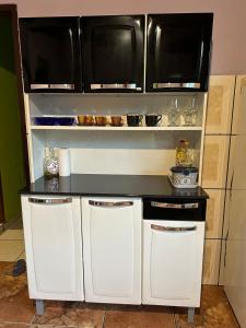 a kitchen with white cabinets and a black counter top at Recanto da Paz - Vale da Prata in Bocaina de Minas