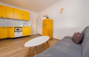 a living room with a couch and a kitchen with yellow cabinets at Nice Apartment In Povljana With Wifi in Povljana