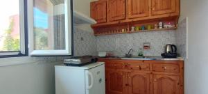 a kitchen with wooden cabinets and a white refrigerator at angelos aparts11 in Arillas +27 photos