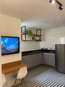 Lindo Apartamento - 600 metros da Praia de Itaparica في فيلا فيلها: مطبخ مع ثلاجة وجهاز تلفزيون على الحائط