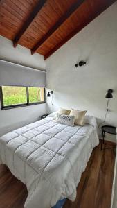Schlafzimmer mit einem großen weißen Bett und einer Holzdecke in der Unterkunft Flusshaus8 in Villa General Belgrano