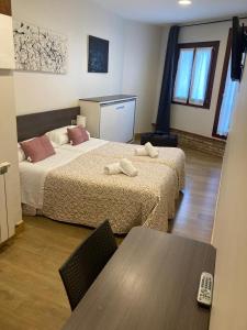 a hotel room with two beds and a table at Pension & resataurante AMAZKAR in Oiartzun