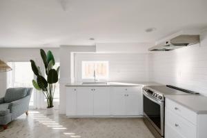 a white kitchen with a sink and a stove at The Little Ray - 2 blocks to Beach - Backyard - Walk to Boardwalk in Carolina Beach