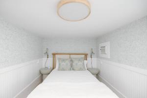 a bedroom with a bed with a white bedspread and a light fixture at The Little Ray - 2 blocks to Beach - Backyard - Walk to Boardwalk in Carolina Beach
