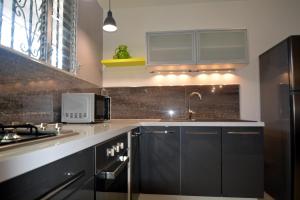 a kitchen with black cabinets and a microwave at Meublé, moderne et tout équipé proche du centre in Fort-de-France