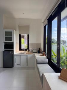 una cucina con mobili bianchi e una grande finestra di The Blue Zone Villa a Nusa Lembongan