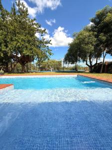 a large blue swimming pool with trees in the background at Mestre Pádel House in San Bernardino