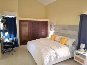 Un dormitorio con una gran cama blanca y un escritorio. en Paramount Views, en San Felipe de Puerto Plata