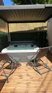 a patio with a table and chairs under a roof at LODGE ESCOVIEN Strasbourg in Eschau