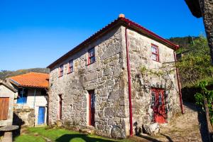 an old stone building with red doors and windows at Casa da Ferreirinha in Sistelo