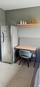 a kitchen with a desk and a refrigerator and a chair at Ap novo, perto de Congonhas, com cama queen size in São Paulo