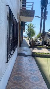 a sidewalk next to a building with a gate and palm trees at Hospedaje Mar de Perlas in Iquique