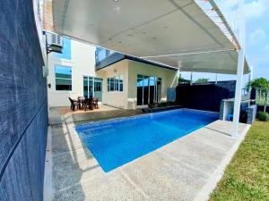 a swimming pool in the backyard of a house with an umbrella at Garden 7 Pool Villa in Sampong