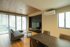 a living room with a table and a television at MOVA VILLA Koshi Misawa 1 in Yuge