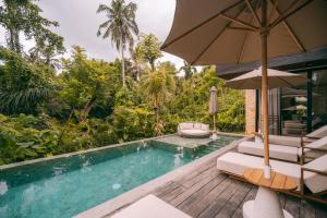 una piscina con due sedie e un ombrellone di Casa Simone ad Ubud