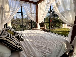 a bedroom with a white bed with curtains and a window at The Castle Uluwatu - Ocean View Luxury villa in Uluwatu +13 photos