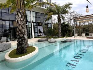 a swimming pool with a palm tree in front of a building at The Castle Uluwatu - Ocean View Luxury villa in Uluwatu