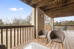 a porch with two chairs and a table on it at Modern Comfort Retreat in Branson