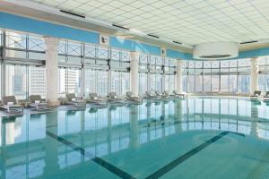 ein großes Schwimmbad mit Stühlen in einem Gebäude in der Unterkunft THE PLAZA Seoul, Autograph Collection in Seoul