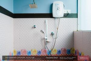 高尔Shirantha Hotel的墙上花卉浴室内的淋浴