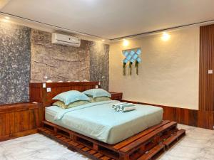 a bedroom with a large bed with a wooden frame at Evergreen Lodge in Padang