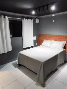 a bedroom with a large bed with white sheets at Loftjesus in Campina Grande