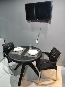 a black table with two chairs and a television on a wall at Loftjesus in Campina Grande