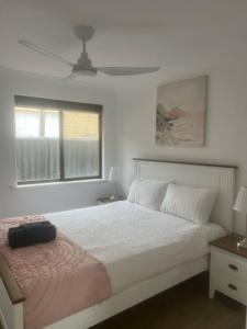 a white bedroom with a bed and a window at Madora Bay Beach House in Singleton +2 photos