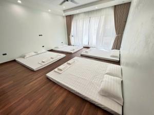 three beds in a room with a large window at Vinhomestay sh19-98 in Hòa Bình