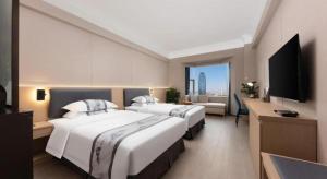 Una habitación de hotel con dos camas y un televisor de pantalla plana. en Greatwall Hotel - Zhengzhou, en Zhengzhou