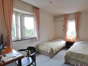土庄町にあるCountry Inn The White Marineのベッド2台、デスク、窓が備わるホテルルームです。