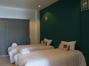 two beds in a room with a green wall at Sabai @ Chumphae Hotel in Chum Phae