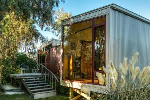 a tiny house with glass doors and stairs at Misty River Retreat in Blenheim