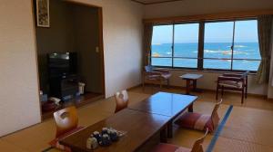 a living room with a table and chairs and a view of the ocean at Daitoku Hotel in Choshi