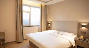 ein Schlafzimmer mit einem großen weißen Bett und einem Fenster in der Unterkunft 7 Days Inn Tianjin Binhai Passenger Station Huabei Ceramics in Binhai + 25 Fotos