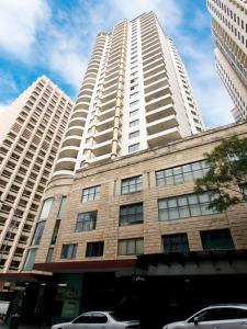 een hoog wit gebouw met auto's geparkeerd voor het bij Oaks Sydney Castlereagh Suites in Sydney