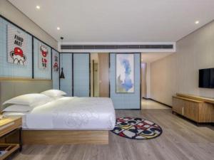 - une chambre avec un grand lit blanc et une télévision à écran plat dans l'établissement JTOUR Inn Yizhou Hechi College Pedestrian Street, à Qingyuan