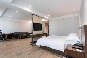 une chambre avec un lit, un bureau et une télévision dans l'établissement Borrman Hotel East Huai'an Railway Station Zhou 'Enlai Memorial, à Hexia