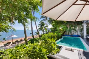 an outdoor swimming pool with an umbrella and the beach at Villa M in Bophut