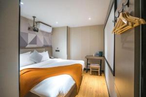 吉安市にあるBorrman Hotel Ji'an Railway Station Jinggangshan Universityのベッドと机があるホテルの部屋 +5枚の写真