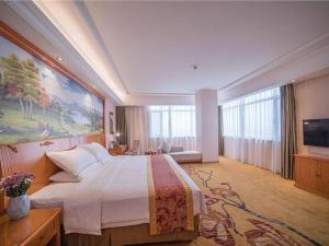 une chambre d'hôtel avec un grand lit et un tableau mural dans l'établissement Vienna Hotel Hebei Tangshan Nanhu Park, à Tangshan 185 autres photos