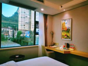 a bedroom with a window with a view of a city at Vienna Hotel Guangxi Hechi Jinchengjiang Baima Street in Hechi