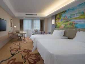 a hotel room with two beds and a painting on the wall at Vienna Hotel Guangxi Wuzhou High-Tech in Wuzhou