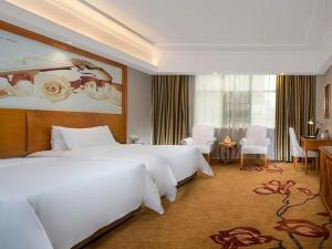 ein Hotelzimmer mit zwei Betten und einem Tisch und Stühlen in der Unterkunft Vienna Hotel Hunan Shaoyang South Railway Station in Shaoyang + 125 Fotos